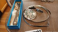 Two Birks sterling silver spoons in a blue box, along with the silver jewelry including a flat silver chain necklace, matched earrings, and brooch with abalone detail.