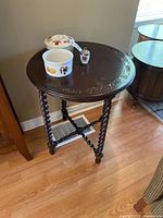 Full view of vintage round accent table with dark wood carved tabletop and barley twist legs, showing scratches and wear.
