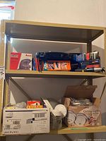Shelf with various boxed and loose items including power tools and lighting components