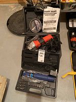 Black & Decker angle grinder in molded black plastic case with instruction manual, Red and black angle grinder with cord.