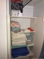 Shelf with folded assorted bath towels stacked in piles by color and fabric style.