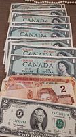 Overview of all bills including nine Canadian 1 dollar bills on top, two Canadian 2 dollar bills beneath, and one USA 2 dollar bill at bottom.