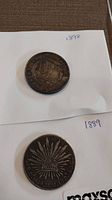 Both silver coins on white paper labeled with their years, 1898 (USA) and 1889 (Mexico).