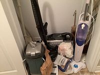 Wide view showing Tri Star vacuum cleaner, hoses and assorted bags and vacuum parts stored in closet.