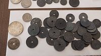 Various vintage Belgium coins spread on white paper, many dark with wear and some pierced through the center.