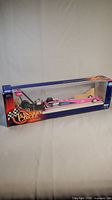 Side view of the boxed die cast dragster car showing clear plastic window and colorful branded packaging.