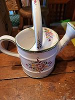 Top angled view showing handle, open top, and floral design on the body and handle.