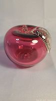 Front view of the cranberry red glass apple with clear glass leaf and stem visible