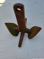 Rusty iron anchor with flukes and shank visible, showing surface rust and weathering.