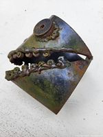 Close-up photo of the iron fish head sculpture showing its open mouth and teeth details made from small welded metal components with surface rust.