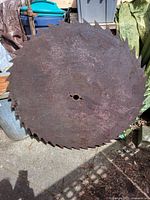 Image of full circular saw blade showing rusted metal surface, jagged teeth edging, central mounting hole