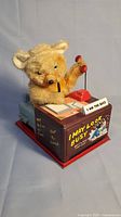 Full view of the battery operated toy bear sitting at a desk with red phone and whimsical slogans on metal sides.