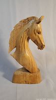 Side view of wooden horse head sculpture showing realistic details and textured mane.