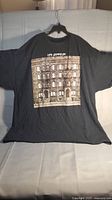 Black XL t-shirt displayed hanging on hanger showing full front view with Led Zeppelin Physical Graffiti album cover print.