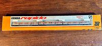 Original box showing the Arnold Rapido branded model train with its three cars in DB orange/beige livery, in unopened condition.
