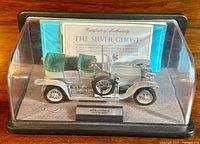 Front-left angled view of 1:24 scale Franklin Mint 1907 Rolls Royce Silver Ghost model car inside display case, showing silver body, green seats, and Certificate of Authenticity in background.