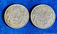 Two 1952 Canadian silver half dollar coins shown side by side on a blue background, displaying the reverse side with the Canadian coat of arms, denomination '50 CENT', and date '1952'.