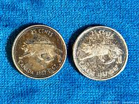 Two 1967 Canadian silver quarters placed side by side on a blue fabric background, showing the wolf design and the 25 cents denomination with 'CANADA 1867-1967' inscription.
