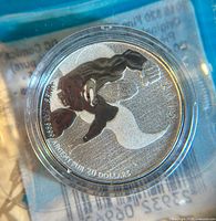 Close-up photo of the front of the Superman silver coin showing the design, year, purity, and face value in plastic capsule within original packaging.