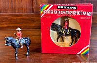 Two hand-painted metal Royal Canadian Mounted Police figurines by Britains, one figurine still sealed in original box, other loose outside the box missing whip accessory.