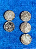 Five Canadian silver dimes in various condition arranged on a blue fabric background. Coins show wear and typical tarnishing.