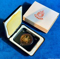 Obverse view of the 1971 British Columbia commemorative silver dollar in the original black and white presentation case with the white Canadian crest box.