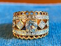 Close-up image of the ring showing the front view with the blue CZ center stone, clear quartz square stones, and the detailed gold-washed sterling silver band with small clear stones.