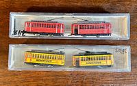 Two sets of Model Power N gauge trolley trains in original clear plastic boxes shown, one in red and one in yellow with 'DOWNTOWN' text.
