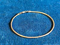 Sterling silver rope design bracelet laid flat on blue fabric showing overall detailing and clasp.