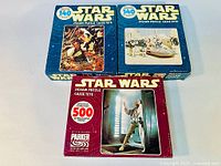 Three vintage Star Wars jigsaw puzzle boxes from 1978 showing different scenes and piece counts, stacked together on a flat surface.