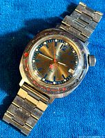 Front and angled close-up of vintage Russian Army mechanical wristwatch with bronze dial, blue and red details, metal case and band.