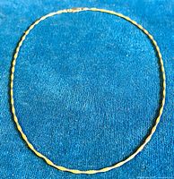 Full view of the vintage twisted sterling silver necklace with gold wash sections laid on a blue fabric background.