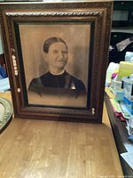 Frontal view of one wooden antique picture frame with a portrait of a woman, showing frame detail and some wear.