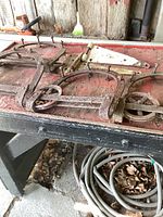 Wide view showing multiple pieces of antique barn door hardware arranged on a wooden surface with visible rust and wear.