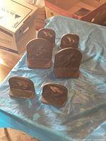 Overview of all six metal bookends on a blue tarp, showing their relative sizes and designs