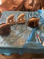 Four elephant bookends displayed on a blue sheet: two light-colored standing elephant bookends and two darker rounded elephant bookends.