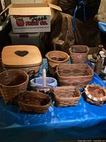 Full lot of eleven assorted baskets of various sizes and shapes, displayed on a blue tarp including Longaberger and Bradford baskets