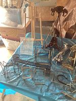 Metal and wooden display stands arranged on a blue cloth surface with various sizes and styles visible.