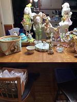 Overview of Easter-themed items including bunny figurines, decorative eggs, basket, and bowls on a wooden table.