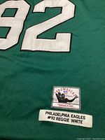 Close-up of the jersey showing the large white stitched number '92' and label reading 'Throwbacks NFL Philadelphia Eagles #92 Reggie White' by Mitchell & Ness.