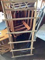 Photo of bamboo hanging display rack leaning against a chair with handmade crates behind it, showing slatted horizontal bars and circular top decoration.