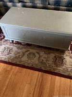 Side view of the light blue wooden storage chest showing decorative front panel and legs.