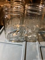 Front and side view of two clear Ball Mason quart glass jars showing embossed logo and text
