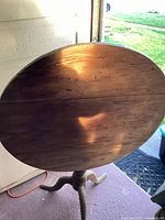 Photo showing the round tabletop with visible wood grain and marks from use, highlighting the brown wood surface and its vintage condition.