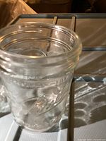Single clear wide mouth pint canning jar, showing embossed detail on glass.