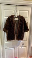 Front view of dark brown fur stole on hanger showing open front