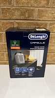 Front of sealed De'Longhi Capsule heater box showing product image and power rating