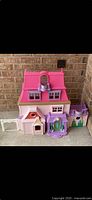 Front view of closed pink and purple dollhouse