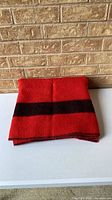 Folded red wool blanket with center black stripe