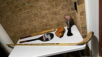 Overall view showing hockey stick, baseball bat, glove, Donnay paddle, TaylorMade headcover on table